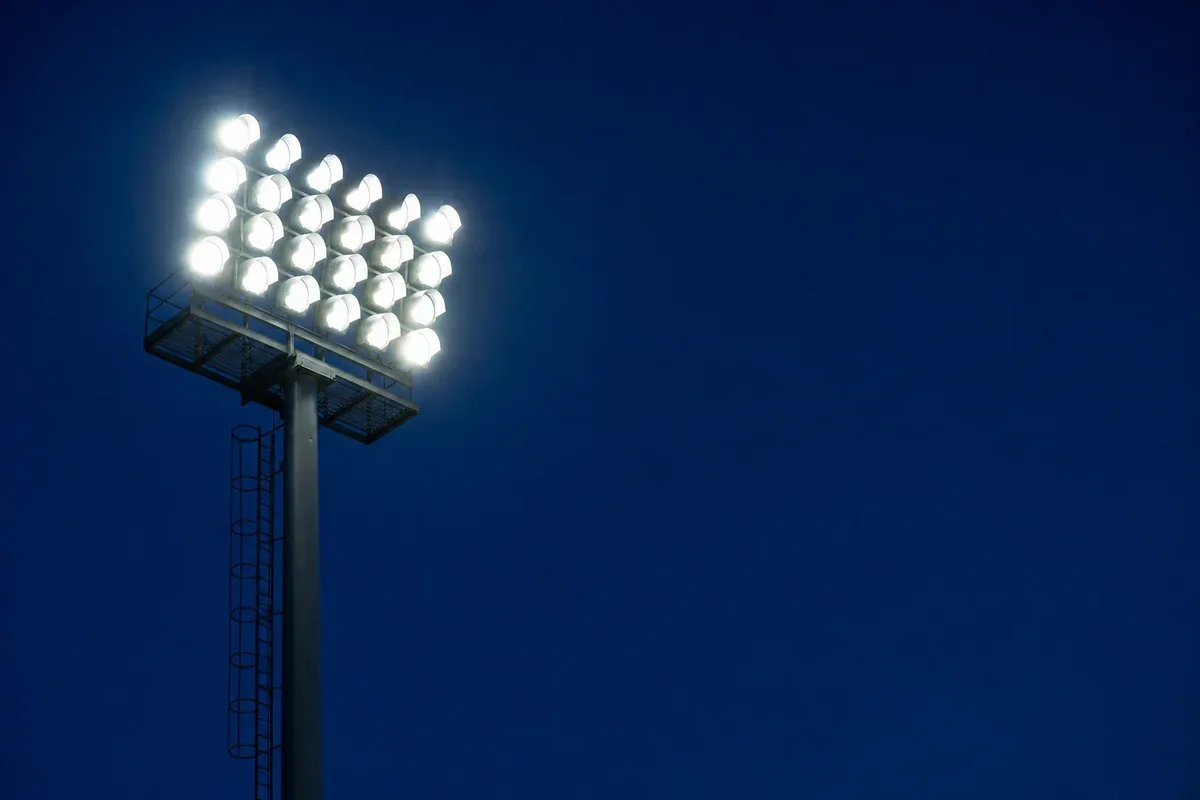 AI – mit künstlicher Intelligenz erzeugtes Bild: Flutlichtmast eines Stadions zur blauen Stunde